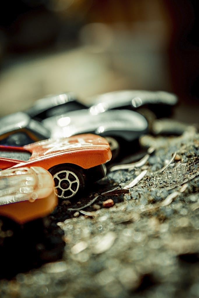 Colorful miniature toy cars on a gravel surface with a blurred background, highlighting playfulness.